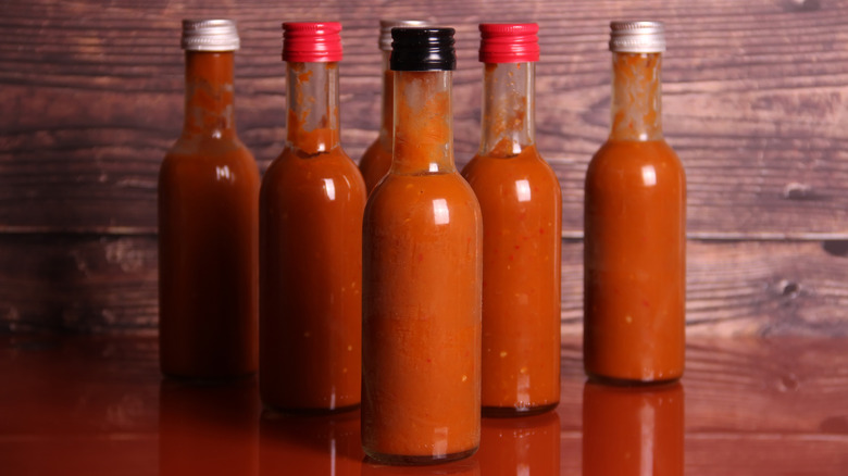 Six bottles of hot sauce arranged in a triangle on a table