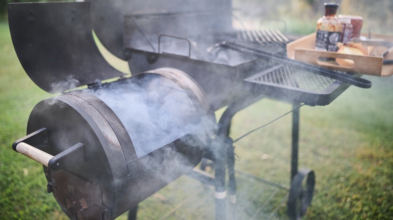 A barbecue smoker with smoke coming out of it outside