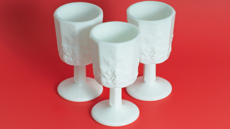 three milk glass goblets on red background