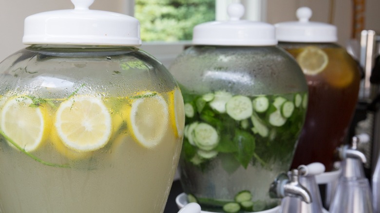 A glass drink dispenser on a wooden table outdoors