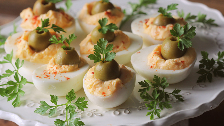 Spicy deviled eggs topped with olives and parsley.