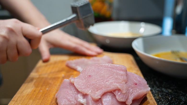 An individual pounding chicken.
