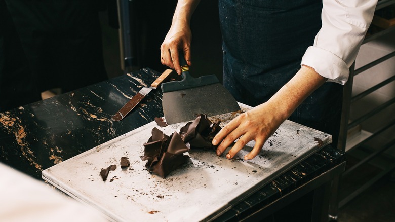 A chef moulding and scraping chocolate on a board