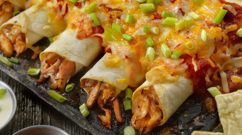 Chicken enchiladas topped with sauce, cheese, and green onions