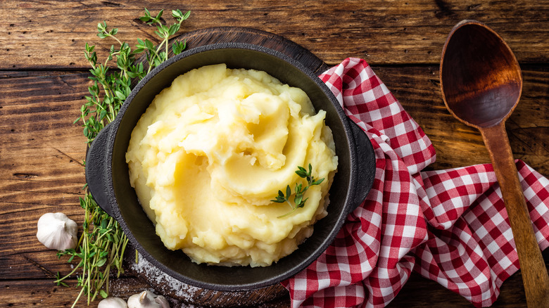 A cast iron pan containing mashed potatoes on a wooden table