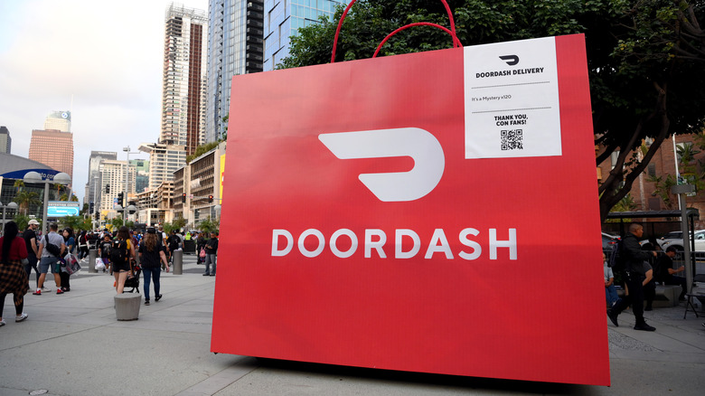 An oversized Doordash delivery bag sits on a sidewalk.