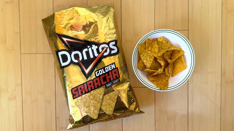 Golden Sriracha Doritos bag next to a bowl filled with the chips.