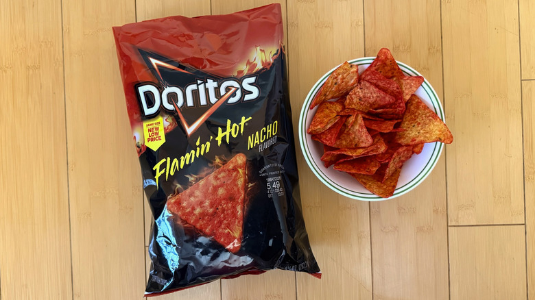 Bag of Flamin' Hot Nacho Doritos beside filled bowl of chips