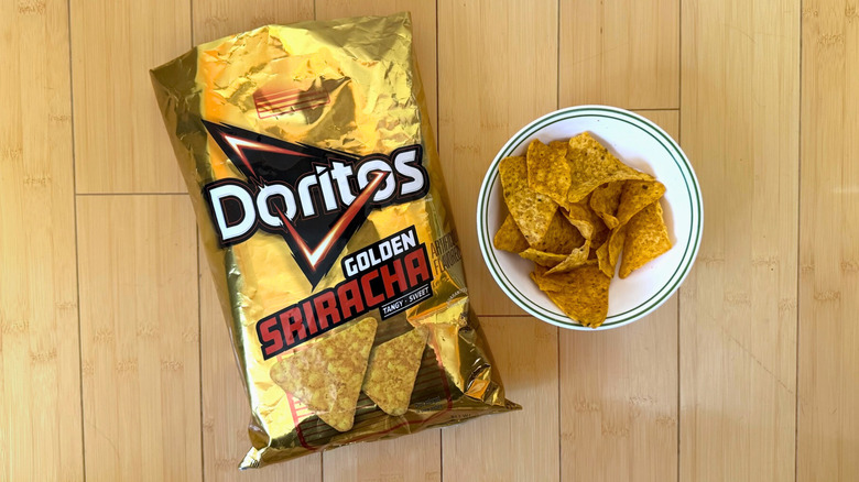 Bag of Golden Sriracha Doritos beside filled bowl of chips
