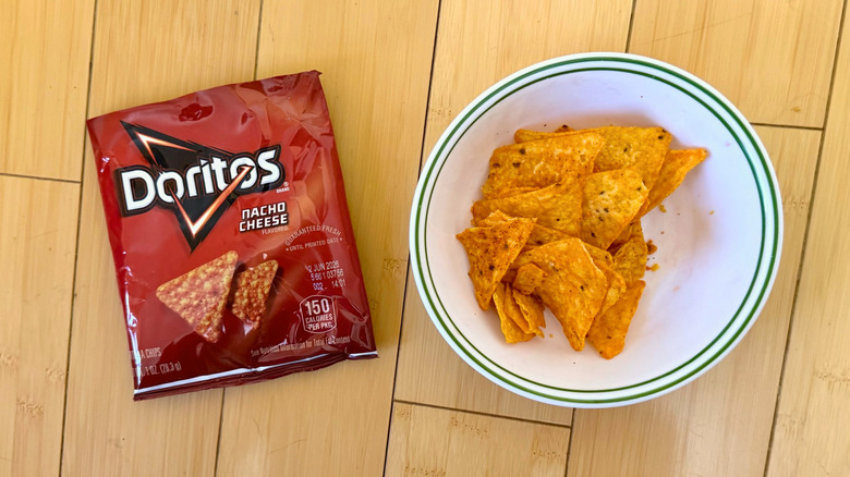 Bag of Nacho Cheese Doritos beside filled bowl of chips