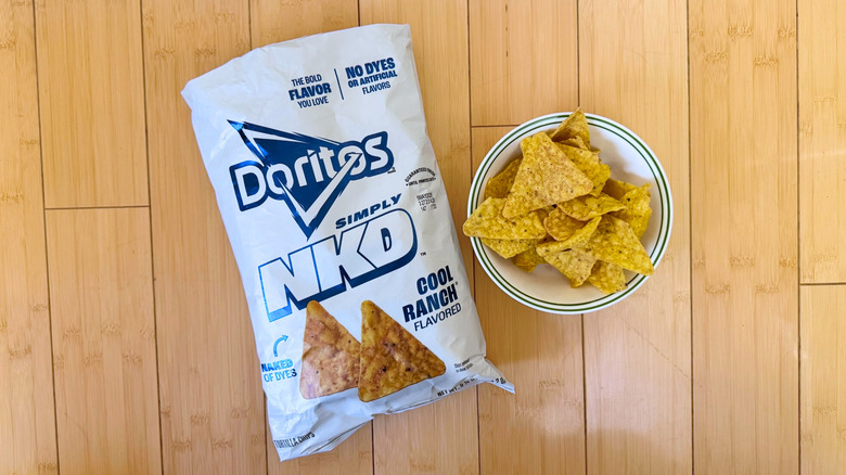 Bag of Simply NKD Cool Ranch Doritos beside filled bowl of chips