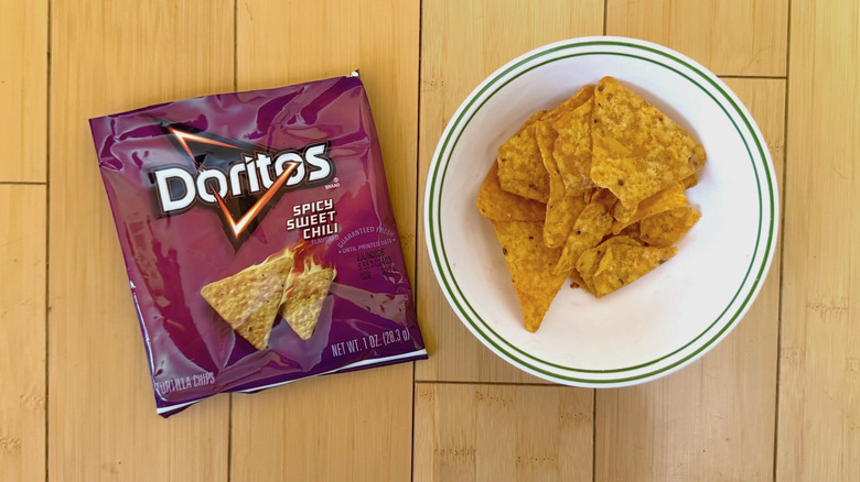 Bag of Spicy Sweet Chili Doritos beside filled bowl of chips