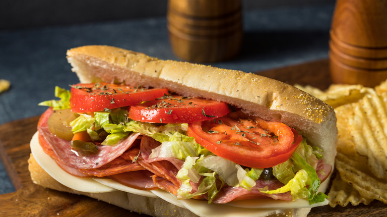 A submarine sandwich  on a wooden board.