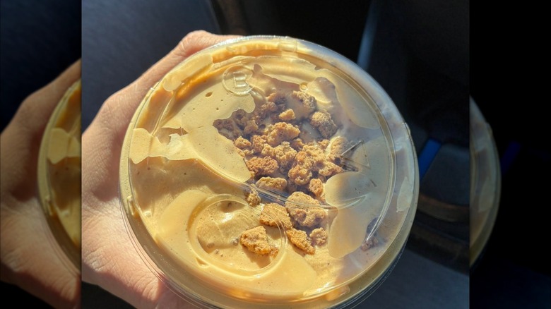 Top-down view of iced coffee topped with cold foam and cookie crumbles.