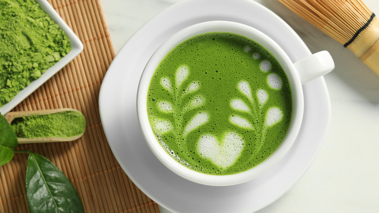 Matcha decorated with latte art in a mug on a white plate