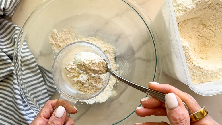 hand spooning flour into cup