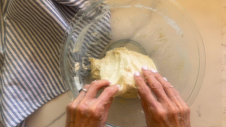 hands folding dough in bowl