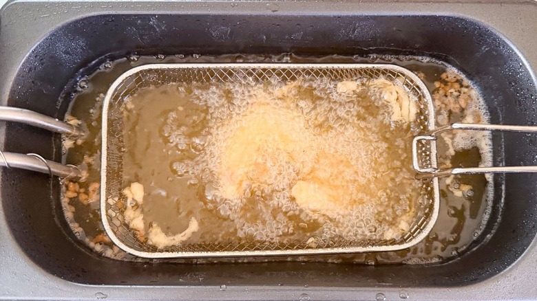 Battered shrimp cooking in fryer with basket