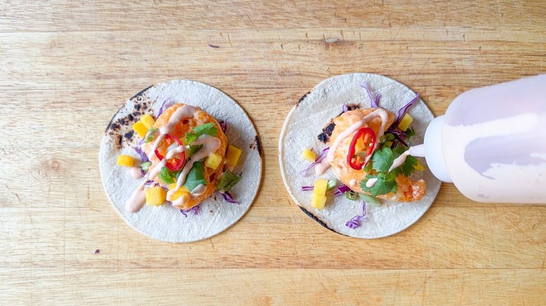 Drizzling dynamite sauce on top of dynamite shrimp tacos