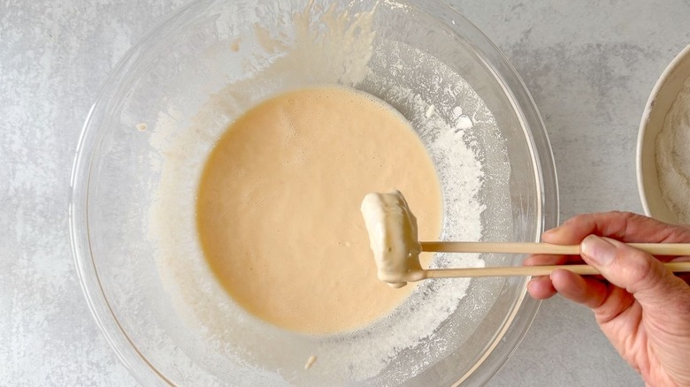 Dipping shrimp into batter using chopsticks