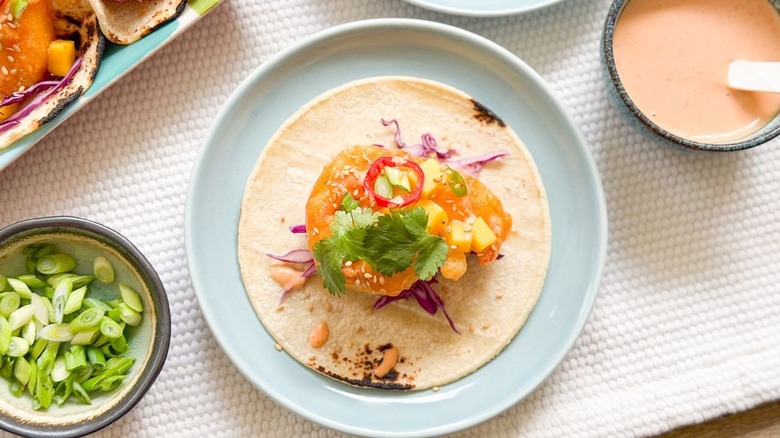Dynamite shrimp taco on plate with bowl of dynamite sauce