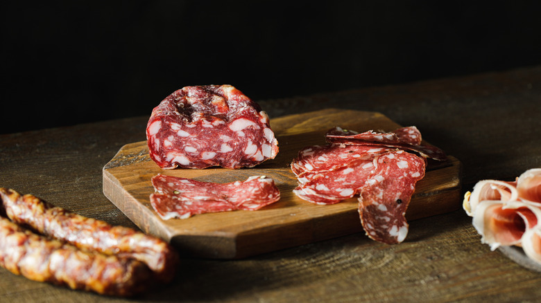 Salami (sliced and unsliced) on a wooden board