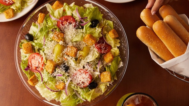 Olive Garden salad next to breadsticks