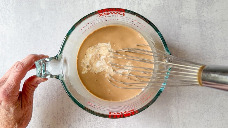 Whisking Vietnamese coffee popsicles base in glass measuring cup