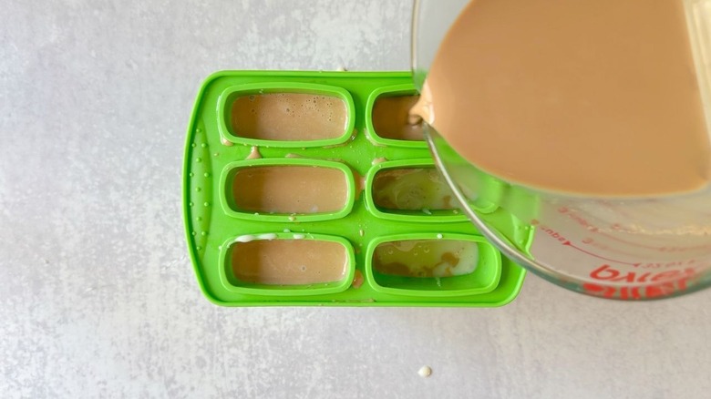 Filling green popsicle molds with Vietnamese coffee
