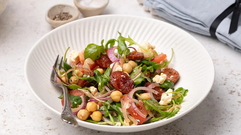 Salad in a dish with chickpeas, red onions, and tomatoes.