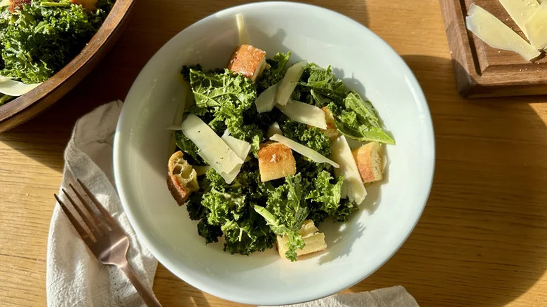 Kale Caesar salad in a bowl on a wooden table.