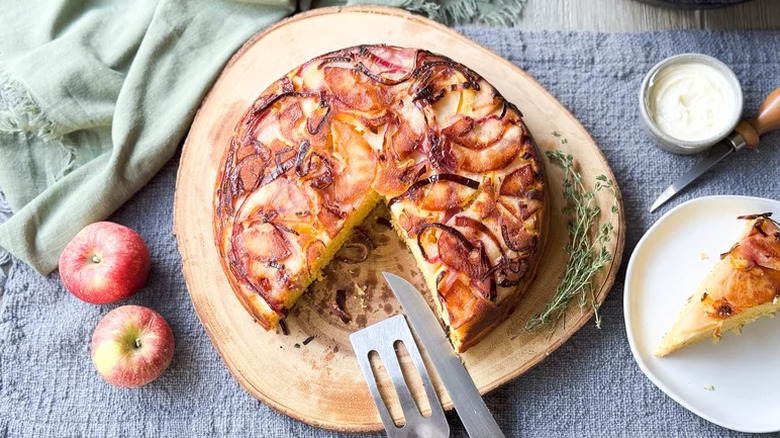 Cornbread with a slice cut out with apples, fresh thyme, and towels.
