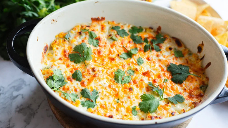 Elote corn dip in a dish with herb topping.