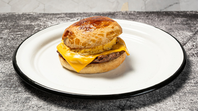 Sausage, egg, and cheese breakfast sandwich on a white plate.