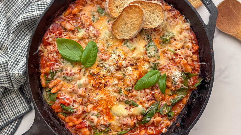 Cheesy pizza beans skillet with basil and baguette slices
