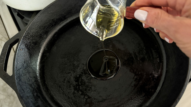 hand adding olive oil to skillet