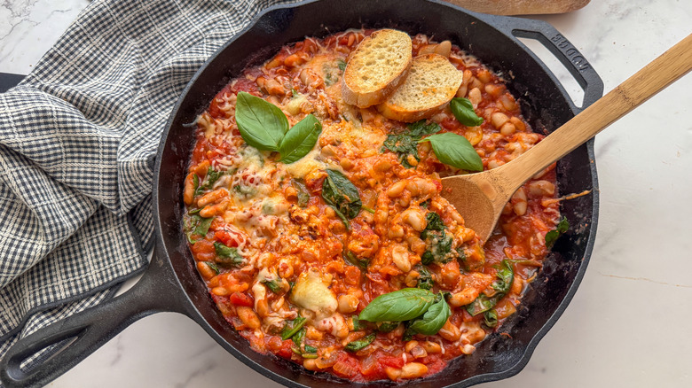 Cheesy pizza beans in skillet with wooden spoon