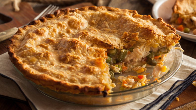 Chicken pot pie in a glass pie dish with a couple of slices removed