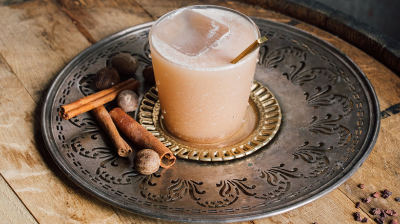 Almond Joy dirty soda in short glass sitting on fancy metal plate