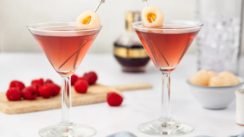 Raspberry Lychee Martinis with fresh raspberries and lychees in the background
