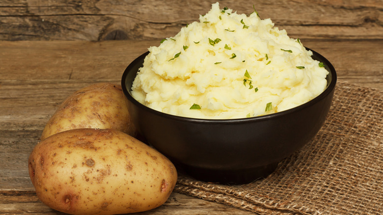 Mashed potatoes, boiled puree in cast iron pot on dark wooden rustic background, top view
