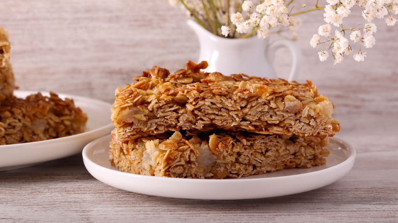 oat bars on plates with a vase and flowers behind