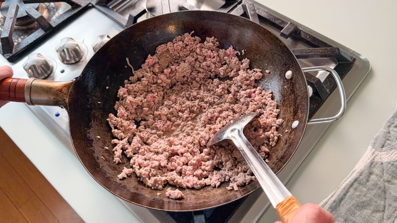 Browning ground pork in wok with spatula