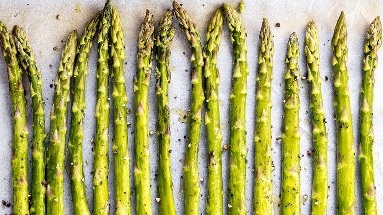 Close-up of evenly-spaced roasted asparagus spears with salt and black pepper