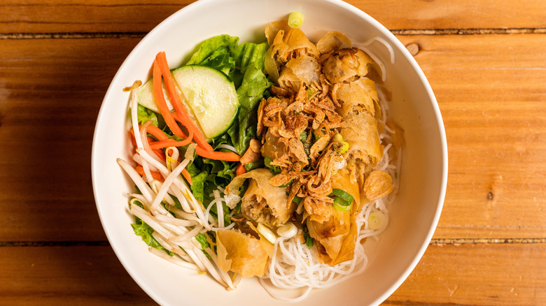 Sliced egg rolls in a bowl with fresh vegetables