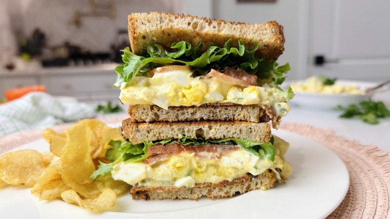 Egg salad club sandwich on plate with chips