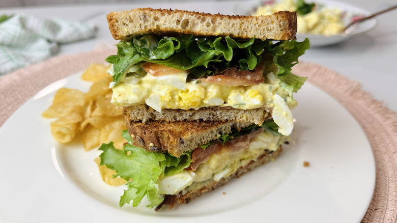 Egg salad club sandwich on plate with chips