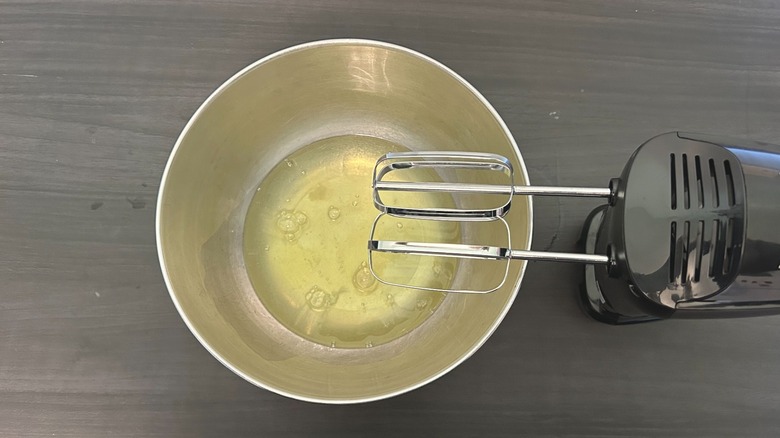 Metal bowl of egg whites ready to be whipped with hand beaters