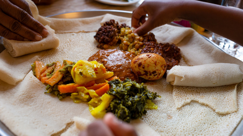 People eating Ethiopian food from an injera