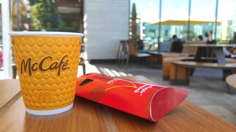 Cup of McCafé coffee on a table next to a container with a McDonald's pie.